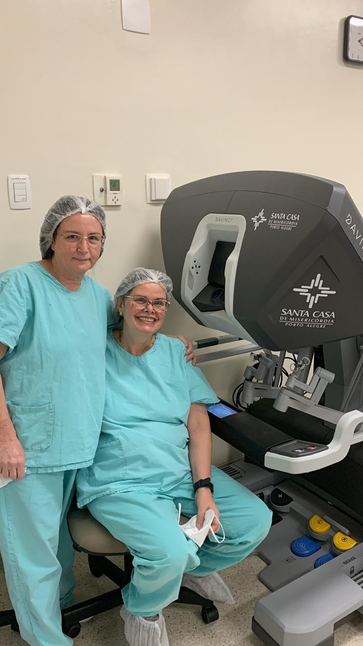 Dra. Lídia Medeiros em centro cirúrgico, ao lado do console de cirurgia robótica da Santa Casa de Porto Alegre